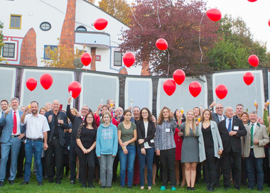 Gruppenfoto der Teilnehmer:innen der ÖJRK-Bundeskonferenz 2011. Einige Personen halten ein Glas Sekt in der Hand und prosten damit zu. Über der Gruppe sind rote Luftballons, die gerade aufsteigen, zu sehen.