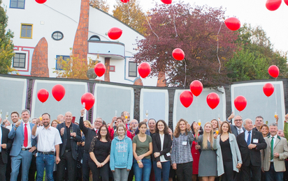 Gruppenfoto der Teilnehmer:innen der ÖJRK-Bundeskonferenz 2011. Einige Personen halten ein Glas Sekt in der Hand und prosten damit zu. Über der Gruppe sind rote Luftballons, die gerade aufsteigen, zu sehen.