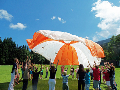 Kinder spielen mit Fallschirm bei ÖJRK-Sommercamp in Wagrain