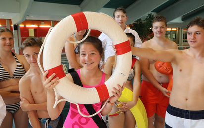 Kinder in Badekleidung blicken durch einen Rettungsreifen