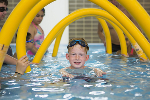 Ein Bub schwimmt in einem Hallenbad im Wasser