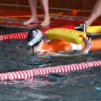 Eine Teilnehmerin transportiert eine Rettungsschwimmpuppe mit Hilfe eines Rettungsgurts im Wasser.