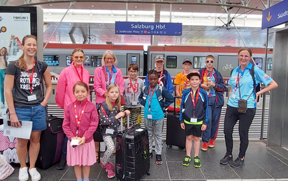 Eine Gruppe von Mädchen und Jungen warten gemeinsam mit ihren Betreuer:innen am Salzburger Hauptbahnhof.