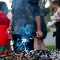 Ein Kind grillt ein Marshmallow auf einem Stock über dem Lagerfeuer.