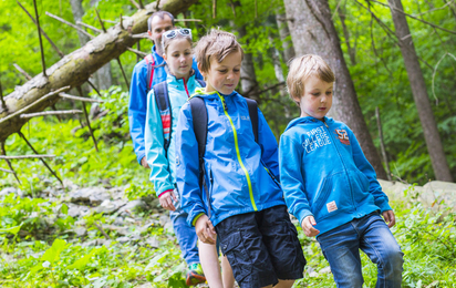 ein Mann und 3 Kinder gehen im Wald spazieren.