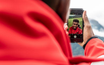 Anas ist geflüchtet und wohnt nun in Tirol. Er trägt schon mit Stolz eine rotes Rotkreuz Jacke und schaut sich dabei selbst in seinem Handy an. Anas ist get social Jugendreporter des Roten Kreuzes