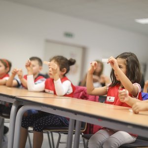 Kinder sitzen in einer Reihe und lernen Pflaster kleben